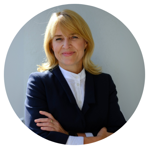 Frau Kay Czachara mit einem legeren dunklen Blazer im Halbprofil lächelnd in die Kamera.